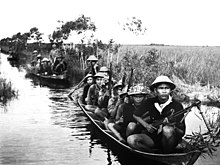 Zachycená fotografie zachycující vietkongské vojáky cestující na člunech s plochým dnem zvaných sampany.