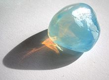 Milky opal is red-orange in transmission because density inhomogeneities scatter the blue light laterally.
