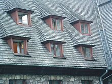 Ein Dach in Polen. Es hat Holzschindeln. Sechs Gauben sind zu sehen