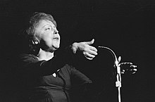 Édith Piaf che canta davanti a un microfono (1962).