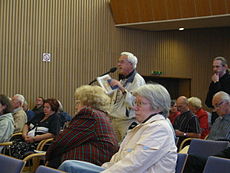 Een burger die een betoog houdt op een stadsvergadering.  