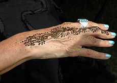 Een uitstekend voorbeeld van handkunst. De hand toont bijpassende turquoise nagels en ring; bruine henna en gouden huidversiering.  