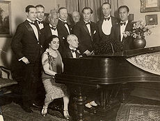 Морис Равел на пианото в акомпанимент на канадската певица Ева Готие 7 март 1928 г., по време на американското му турне. Джордж Гершуин стои в крайния десен ъгъл.