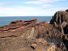 Siccar Point, Berwickshire. L'aspro punto mostra letti in leggera pendenza di arenaria rossa vecchia del Devoniano di 345 milioni di anni sopra letti verticali di grigia siluriana di 425 milioni di anni. Questo era uno dei siti discussi da Hutton.