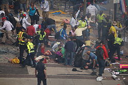 Pēc sprādzieniem Bostonas maratonā daudzus cilvēkus no atasiņošanas izglāba pirmā palīdzība. Šajā fotoattēlā redzami cilvēki, kas sniedz pirmo palīdzību, lai apturētu asiņošanu.