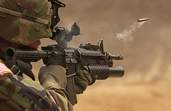 Amerikaanse soldaat vuurt een M-4 geweer af. Een huls van een huls (het losgemaakte achterste gedeelte van een kogel) vliegt eruit.