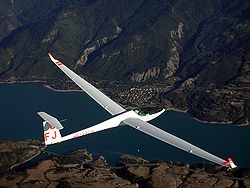 Modern zweefvliegtuig vliegend boven een meer genaamd het Lac de Serre Ponçon in de Franse Alpen