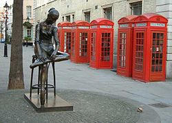 Červené telefonní budky K2 za bronzovou sochou Enza Plazzotty "Mladý tanečník" na Broad Street, Covent Garden, Londýn  