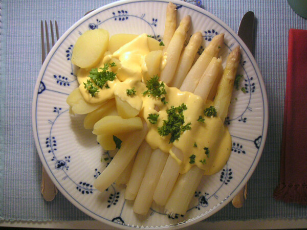 Hollandaise saus geserveerd over witte asperges en aardappelen