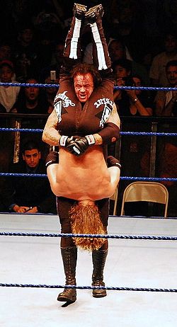 Undertaker execută Tombstone Piledriver asupra lui Edge