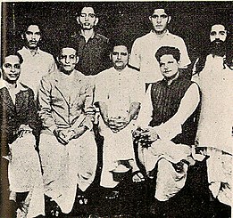 Foto de grupo de los acusados del asesinato de Mahatma Gandhi. De pie (de izquierda a derecha): Shankar Kistaiya, Gopal Goatse, Madan Lal Pahwa, Digambar Ramchandra Badge]. Sentados (de izquierda a derecha): Narayan Apte, Vinayak Damodar Savarkar, Nathuram Goatse, Vishnu Ramkrishna Karkare  
