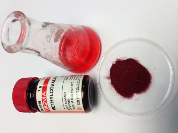 メチルコバラミン（表示）は、ビタミンB12の一形態です。濃い赤色の結晶は、水の中で桜色の透明な溶液を形成します。