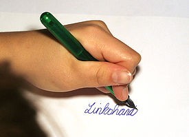 Eine Person, die mit der linken Hand das holländische Wort "Linkshandig" (Linkshänder) schreibt.