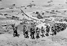 De opbouw op Omaha Beach: versterkingen van mannen en materieel trekken landinwaarts 7 juni 1944  