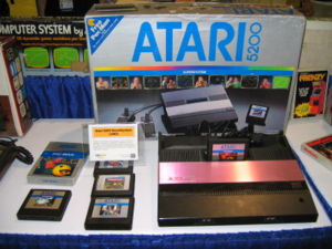 Atari 5200 -järjestelmä ohjaimineen, pelikasetteineen ja pakkauksineen.