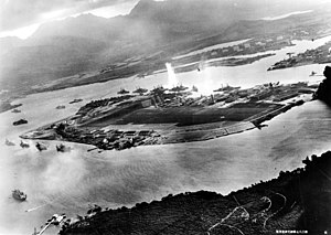 Attack on the ships lying in the harbor. In the center, an explosion following a torpedo hit on the USS Oklahoma. Two attacking Japanese aircraft can be seen: one over the USS Neosho and one over the Navy Yard (shot from an attacking Japanese aircraft).