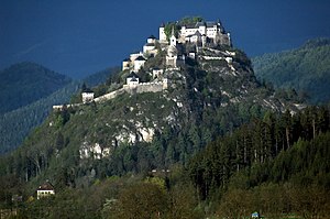 Ett medeltida slott på en kulle med flera väggar och hinder är ett exempel på ett djupförsvar.  