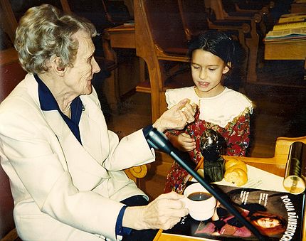 Astrid Lindgren får 1994 det alternativa Nobelpriset (Right Livelihood Award) i den svenska riksdagen. På bordet står priset och ett program för den tyska musikalen om hennes bok "Rånardotter Ronia (kompositör: Axel Bergstedt), som hade givits för första gången samma månad."  