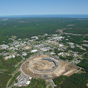 Brookhaven National Laboratory site 2010: In the foreground, the National Synchrotron Light Source II, which was under construction at the time; in the upper right, the Relativistic Heavy Ion Collider; in between, several shutdown research facilities such as the Brookhaven Graphite Research Reactor and the High Flux Beam Reactor. (view to northwest)