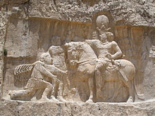 Triumphal relief of the Sassanid Shapur I at Naqsh-i Rustam: Before the Persian king (on horseback) kneels the emperor Philip Arabs; the emperor Valerian stands beside Shapur, who has seized him by the arm as a sign of his capture.