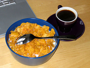 Un bol de céréales pour le petit déjeuner avec une tasse de café.