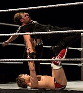 Bryan aplicando uma prancha de surf em Dean Ambrose