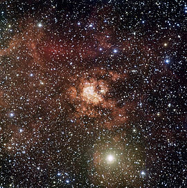 De enorme stellaire kinderkamer Gum 29. In het centrum ervan bevindt zich de sterrenhoop Westerlund 2. Onderaan de sterrenhoop bevindt zich een stelsel van twee van de zwaarste sterren die de sterrenkundigen kennen.