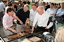Voormalig premier Kevin Rudd helpt mee aan de barbecue.  