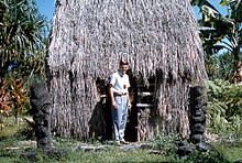 Patung-patung Tiki di depan hale (rumah) tradisional Hawaii. Atraksi wisata, 1959