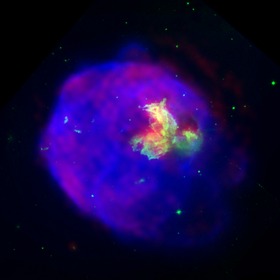 Supernovaremsan LMC N 63A avbildad i röntgenstrålning (blått), optisk strålning (grönt) och radiostrålning (rött). Röntgenljuset kommer från material som värms upp till cirka tio miljoner grader Celsius av en chockvåg som uppstod vid supernovaexplosionen.  