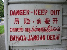 Viertalig waarschuwingsbord, geschreven in de vier officiële talen van Singapore: Engels, Chinees (vereenvoudigd), Tamil en Maleis.
