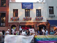 De Stonewall Inn in New York City, waar de Stonewall-rellen van juni 1969 het begin waren van de moderne LGBT-rechtenbeweging. In het gebouw hangen vlaggen met de kleuren van de regenboog, een symbool van LGBT-trots.  