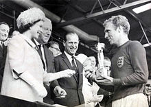 De koningin overhandigt de wereldbeker van 1966 aan Bobby Moore, aanvoerder van het winnende Engelse team. De wedstrijd werd gespeeld tussen Engeland en West-Duitsland op 30 juli 1966 in het Wembley stadion. Engeland won met 4-2 na extra tijd.  