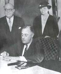 Franklin D. Roosevelt (center) and Secretary of Labor Frances Perkins (right) at the signing of the Wagner Act (1935).