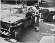 Técnicos fotográficos civiles (en la parte trasera del jeep) que trabajan para el Cuerpo de Contrainteligencia son contabilizados en un puesto de control en Potsdam, Alemania (14 de julio de 1945)